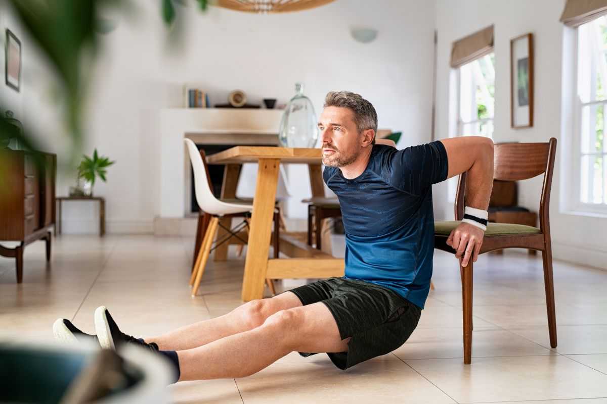 Uomo si allena in casa con una sedia