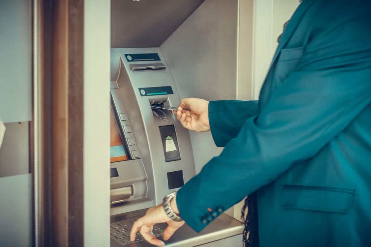 persona che inserisce la carta nello sportello atm