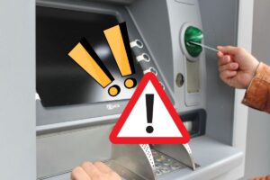 persona che mette la carta nel bancomat e cartello di pericolo