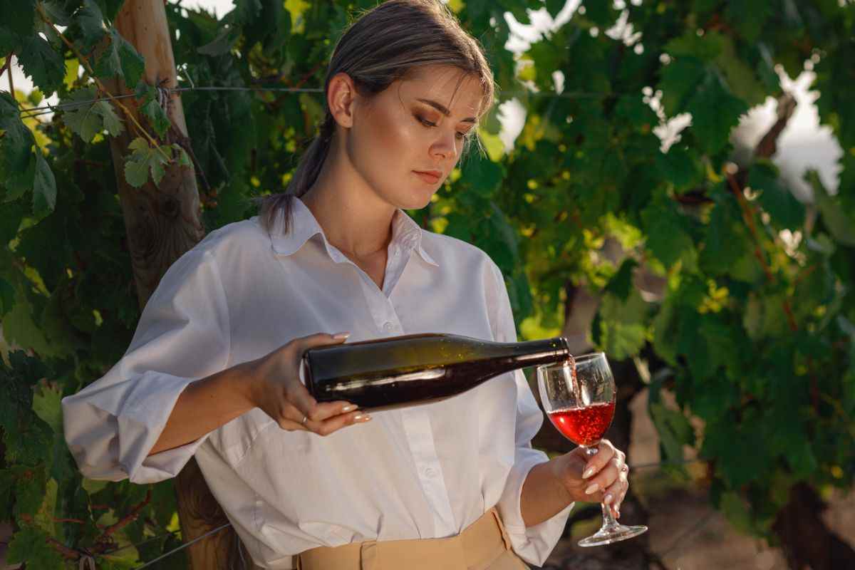 donna che versa un calice di vino rosso