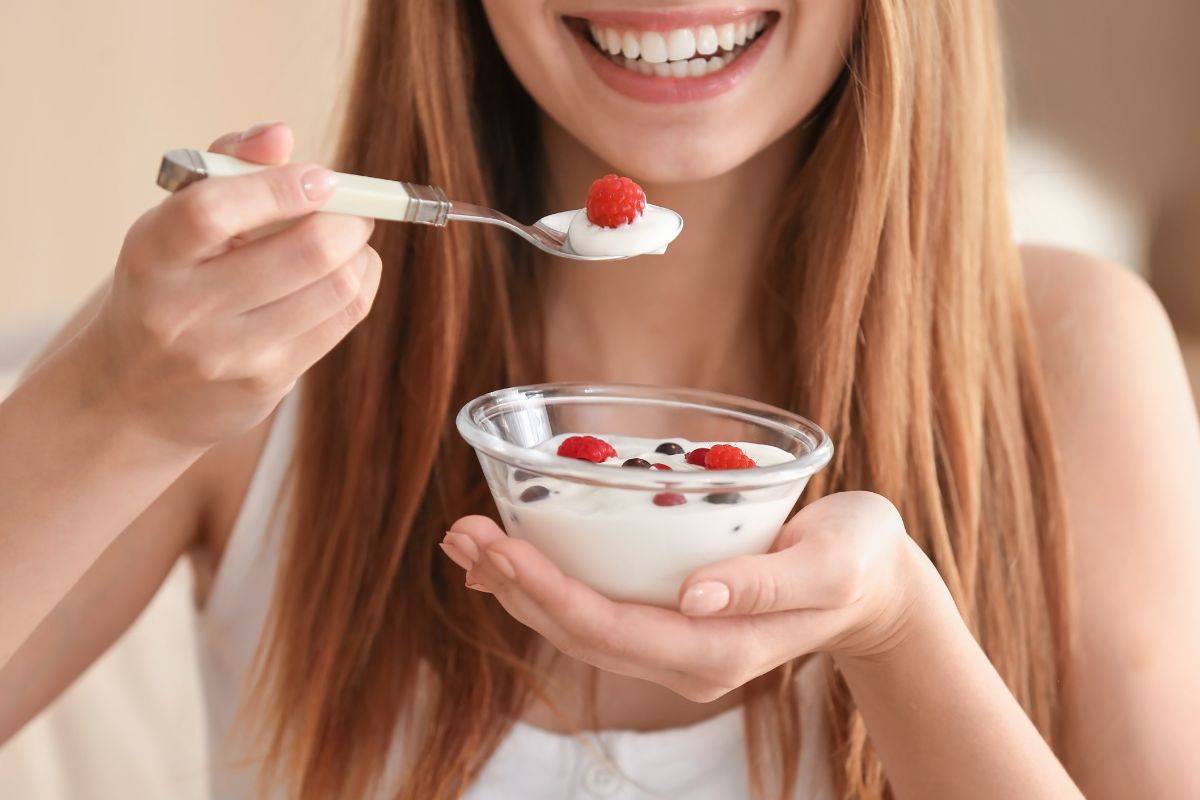 Ragazza mangia yogurt bianco con frutta